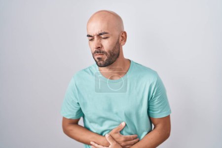 Photo for Middle age bald man standing over white background with hand on stomach because indigestion, painful illness feeling unwell. ache concept. - Royalty Free Image