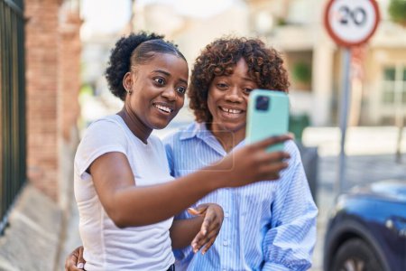 Téléchargez les photos : Les femmes afro-américaines mère et fille font du selfie par smartphone dans la rue - en image libre de droit
