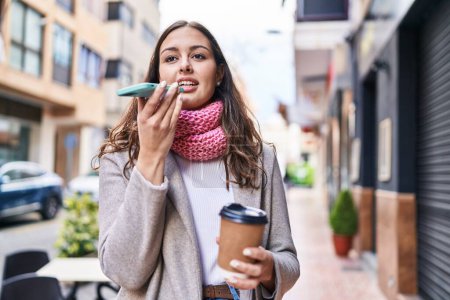 Téléchargez les photos : Young beautiful hispanic woman using smartphone drinking coffee at street - en image libre de droit