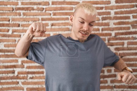 Photo for Young caucasian man standing over bricks wall stretching back, tired and relaxed, sleepy and yawning for early morning - Royalty Free Image