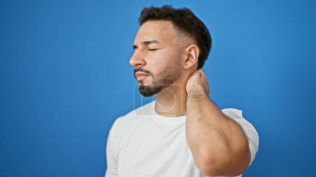 Photo for Young arab man suffering for cervical pain over isolated blue background - Royalty Free Image