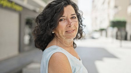 Foto de Mujer hispana de mediana edad sonriendo confiada de pie en la calle - Imagen libre de derechos