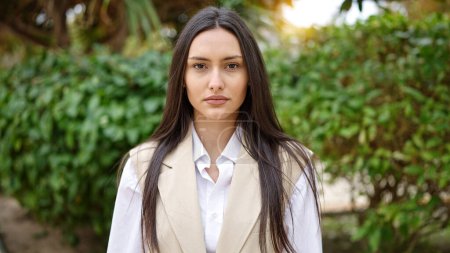 Téléchargez les photos : Jeune belle femme hispanique debout avec une expression sérieuse au parc - en image libre de droit