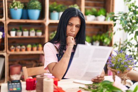 Photo for Middle age hispanic woman florist reading document at florist - Royalty Free Image