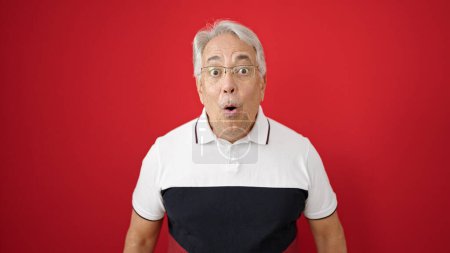 Photo for Middle age man with grey hair standing with surprise expression over isolated red background - Royalty Free Image