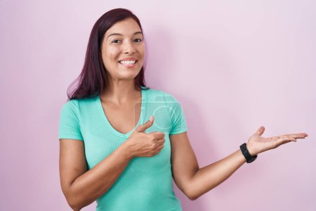 Photo for Young hispanic woman standing over pink background showing palm hand and doing ok gesture with thumbs up, smiling happy and cheerful - Royalty Free Image