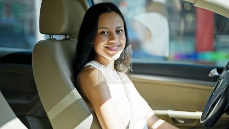 Téléchargez les photos : Jeune belle femme hispanique souriant voiture de conduite confiante à la rue - en image libre de droit