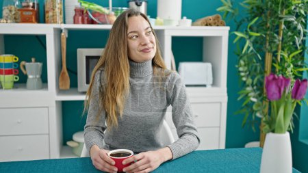 Photo for Young caucasian woman drinking coffee sitting on table at dinning room - Royalty Free Image
