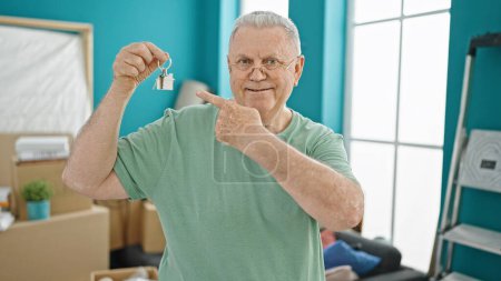 Photo for Middle age grey-haired man smiling confident pointing to keys at new home - Royalty Free Image
