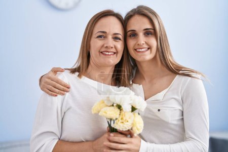 Foto de Dos mujeres madre e hija sorprenden con flores en casa - Imagen libre de derechos