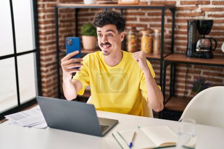 Photo for Hispanic man doing video call with smartphone screaming proud, celebrating victory and success very excited with raised arm - Royalty Free Image