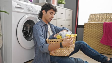Photo for Young hispanic man washing clothes stressed at laundry room - Royalty Free Image
