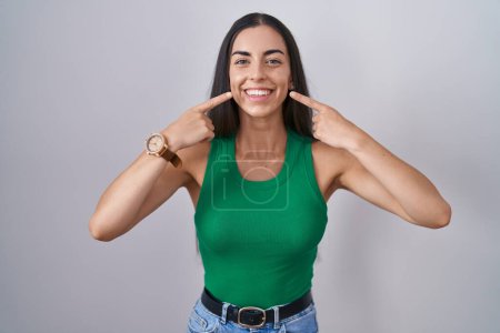 Téléchargez les photos : Jeune femme debout sur fond isolé souriant gai montrant et pointant avec les doigts dents et la bouche. concept de santé dentaire. - en image libre de droit
