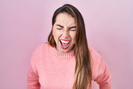 Téléchargez les photos : Jeune femme hispanique debout sur fond rose en colère et fou hurlant frustré et furieux, criant de colère. rage et concept agressif. - en image libre de droit
