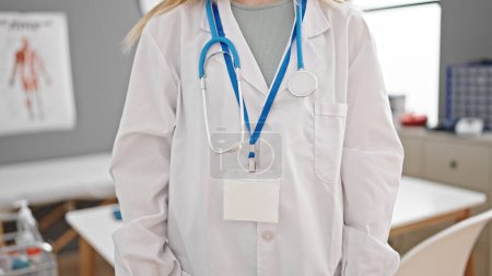 Téléchargez les photos : Jeune femme blonde médecin debout à la clinique - en image libre de droit