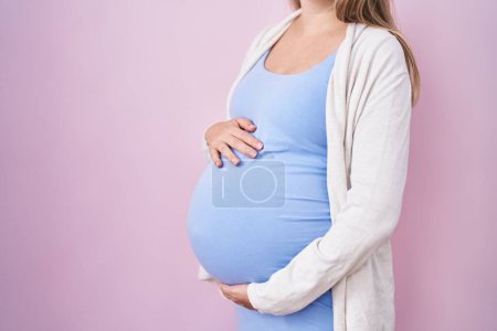 Téléchargez les photos : Jeune femme enceinte attendant un bébé, touchant ventre enceinte effrayé et étonné avec la bouche ouverte pour la surprise, visage incrédule - en image libre de droit