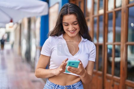 Photo for Young hispanic woman smiling confident using smartphone at street - Royalty Free Image