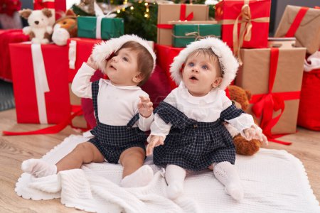 Photo for Two adorable babies sitting on floor by christmas gifts at home - Royalty Free Image