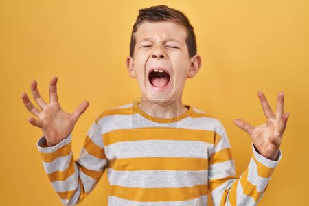 Photo for Young caucasian kid standing over yellow background celebrating mad and crazy for success with arms raised and closed eyes screaming excited. winner concept - Royalty Free Image
