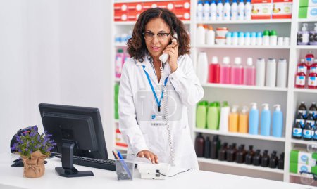 Foto de Farmacéutica de mediana edad hablando por teléfono en la farmacia - Imagen libre de derechos