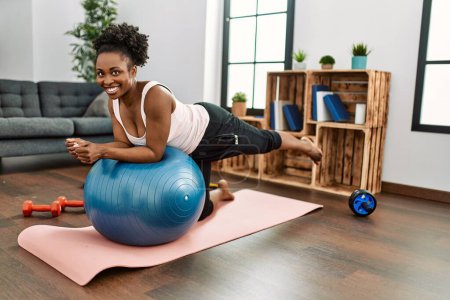 Photo for African american woman training abs exercise using fit ball at home - Royalty Free Image