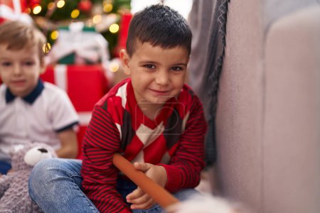 Photo for Two kids playing with toys sitting on floor by christmas tree at home - Royalty Free Image