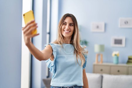 Téléchargez les photos : Jeune femme faire selfie par smartphone debout à la maison - en image libre de droit