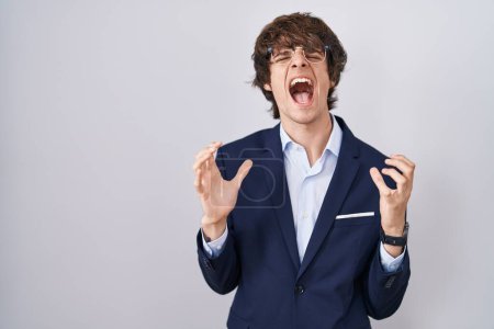 Foto de Joven empresario hispano con gafas locas y locas gritando y gritando con expresión agresiva y brazos levantados. concepto de frustración. - Imagen libre de derechos