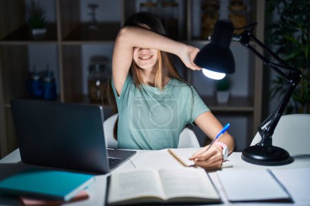 Photo for Teenager girl doing homework at home late at night smiling cheerful playing peek a boo with hands showing face. surprised and exited - Royalty Free Image