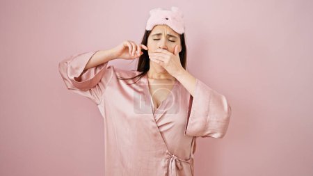 Photo for Young beautiful hispanic woman wearing sleep mask waking up yawning over isolated pink background - Royalty Free Image