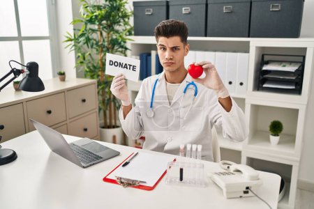 Photo for Young hispanic doctor man supporting organs donations skeptic and nervous, frowning upset because of problem. negative person. - Royalty Free Image