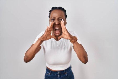 Téléchargez les photos : Belle femme noire debout sur fond isolé criant en colère à haute voix avec les mains sur la bouche - en image libre de droit