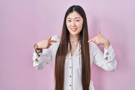 Téléchargez les photos : Chinese young woman standing over pink background looking confident with smile on face, pointing oneself with fingers proud and happy. - en image libre de droit