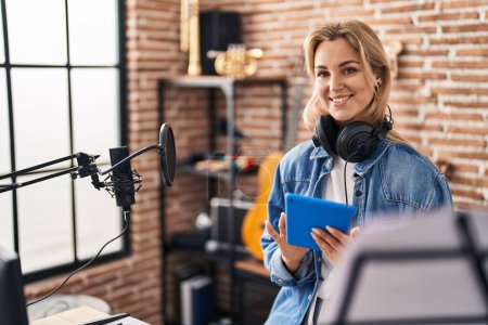 Téléchargez les photos : Jeune femme blonde artiste chantant chanson en utilisant touchpad au studio de musique - en image libre de droit