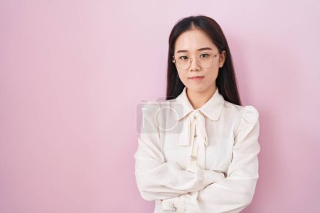 Téléchargez les photos : Jeune femme chinoise debout sur fond rose sceptique et nerveux, expression désapprobatrice sur le visage avec les bras croisés. personne négative. - en image libre de droit