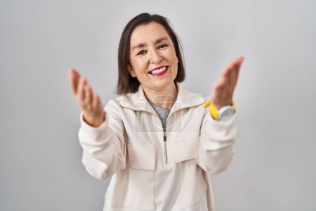 Photo for Middle age hispanic woman standing over isolated background smiling cheerful offering hands giving assistance and acceptance. - Royalty Free Image