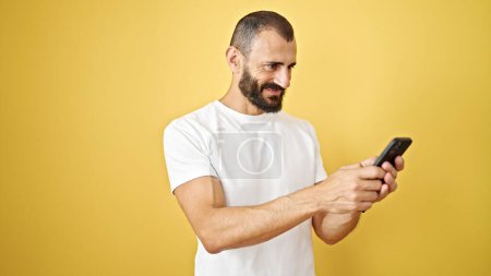 Photo for Young hispanic man using smartphone smiling over isolated yellow background - Royalty Free Image