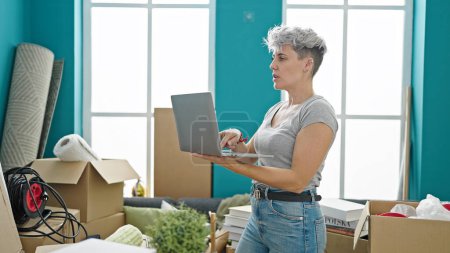 Photo for Young woman using laptop standing at new home - Royalty Free Image