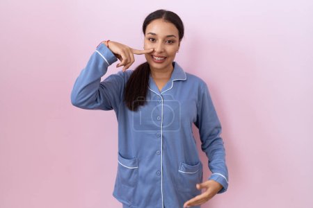 Photo for Young arab woman wearing blue pajama pointing with hand finger to face and nose, smiling cheerful. beauty concept - Royalty Free Image
