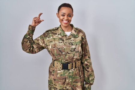 Téléchargez les photos : Belle femme afro-américaine portant uniforme camouflage armée geste souriant et confiant avec la main faisant signe de petite taille avec les doigts à la recherche et la caméra. concept de mesure. - en image libre de droit