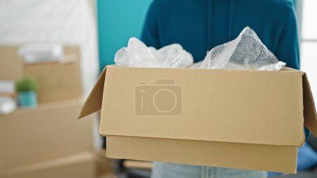 Téléchargez les photos : Jeune homme hispanique tenant paquet à la nouvelle maison - en image libre de droit