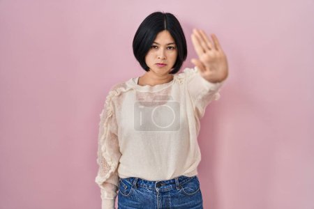 Téléchargez les photos : Young asian woman standing over pink background doing stop sing with palm of the hand. warning expression with negative and serious gesture on the face. - en image libre de droit