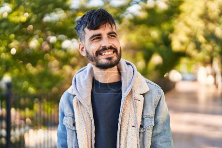 Téléchargez les photos : Jeune homme hispanique souriant confiant regardant vers le côté au parc - en image libre de droit