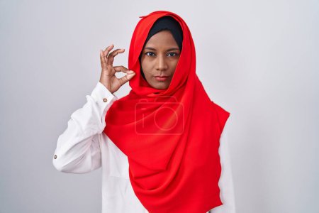 Foto de Mujer árabe joven que usa la tradicional bufanda islámica hijab boca y labios cerrados como cremallera con los dedos. secreto y silencioso, tabú hablando - Imagen libre de derechos