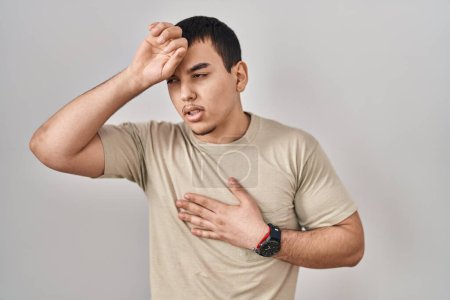 Téléchargez les photos : Jeune homme arabe portant un t-shirt décontracté touchant le front pour la maladie et la fièvre, la grippe et le rhume, virus malade - en image libre de droit
