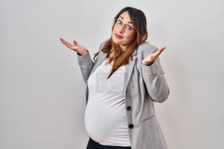 Photo for Pregnant business woman standing over white background clueless and confused expression with arms and hands raised. doubt concept. - Royalty Free Image