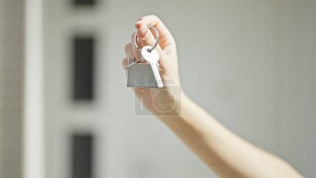 Photo for Young blonde woman real state agent holding keys of new home at street - Royalty Free Image