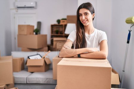 Photo for Young beautiful hispanic woman smiling confident leaning on package at new home - Royalty Free Image