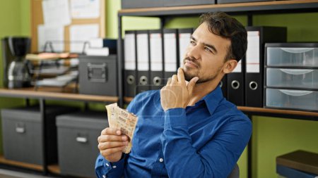 Foto de Joven trabajador de negocios hispano contando billetes mexicanos en la oficina - Imagen libre de derechos