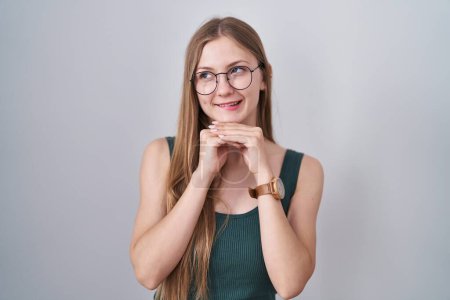 Téléchargez les photos : Jeune femme caucasienne debout sur fond blanc riant nerveux et excité avec les mains sur le menton regardant vers le côté - en image libre de droit